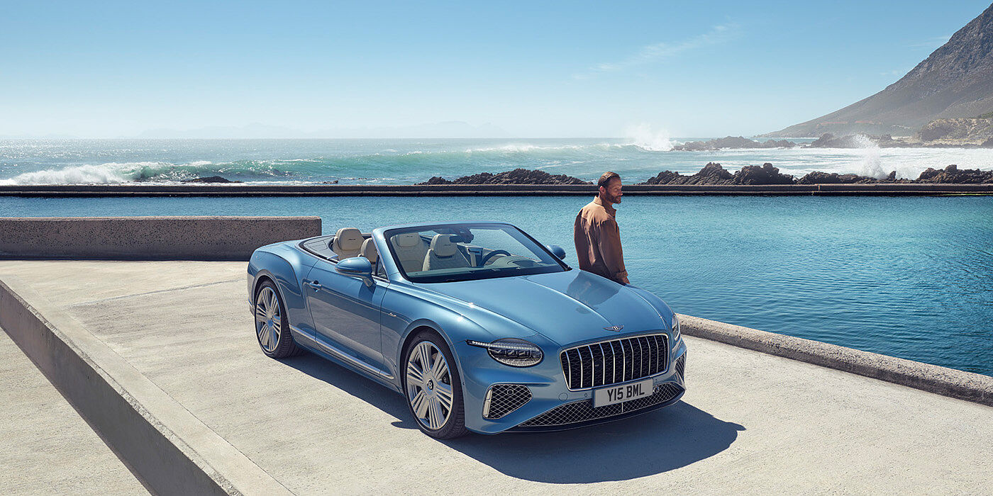 Bentley Vilnius New Bentley Continental GTC Azure convertible front view in Light Windsor blue paint with 22 inch ten spoke wheels parked by the sea in the sunshine