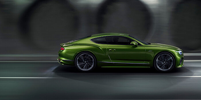  Bentley Vilnius Bentley Continental GT coupe in Tourmaline Green paint driving in profile on a dark road