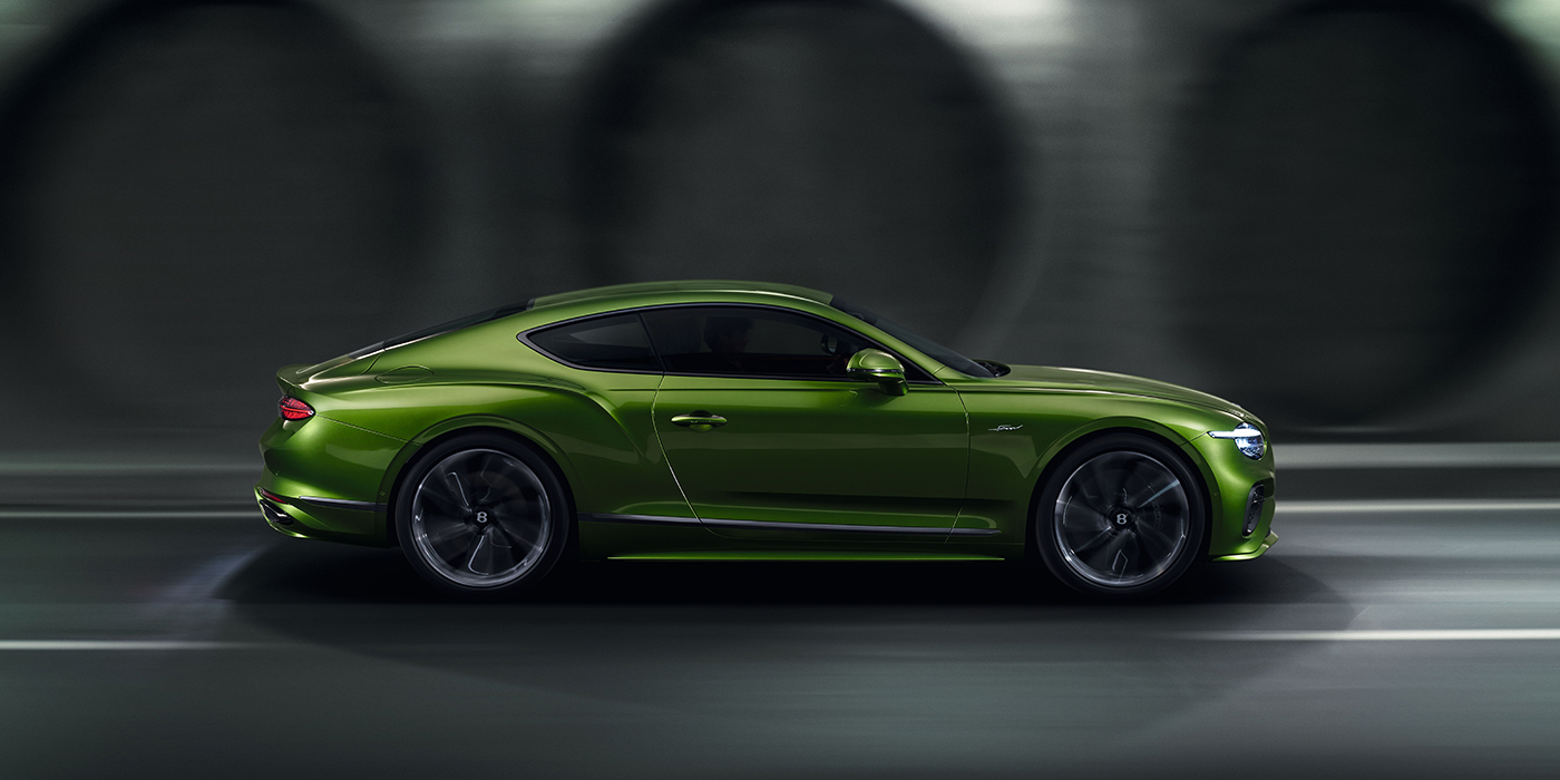 Bentley Vilnius Bentley Continental GT coupe in Tourmaline Green paint driving in profile on a dark road
