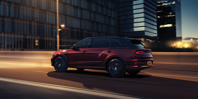 Bentley Vilnius Bentley Bentayga Extended Wheelbase Mulliner SUV in Cricket Ball red paint driving dynamically in city at night