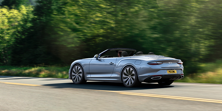Bentley Vilnius New Bentley Continental GTC convertible side view in Silverlake paint with 22 inch ten spoke wheels driving dynamically on a country road
